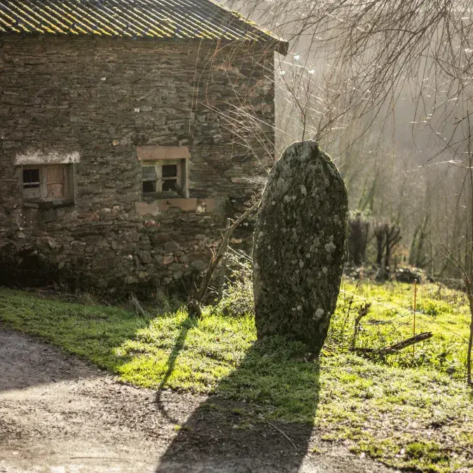 Statue-menhir près d'un bâtiment en pierre, l'hiver